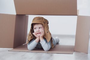 Child preschooler boy playing inside paper box. Childhood, repairs and new house concept